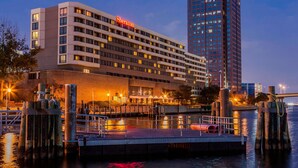 A Sheraton hotel with a modern design, located near a waterfront with a dock and a bridge in the background. - Sheraton Norfolk Waterside Hotel (Norfolk)