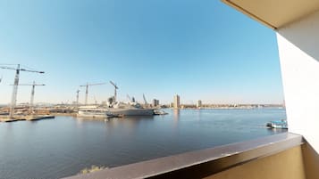 A harbor with a large ship docked, cranes, and a city skyline in the background.