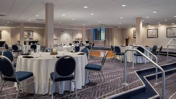 A conference room with round tables, chairs, and a carpeted floor.