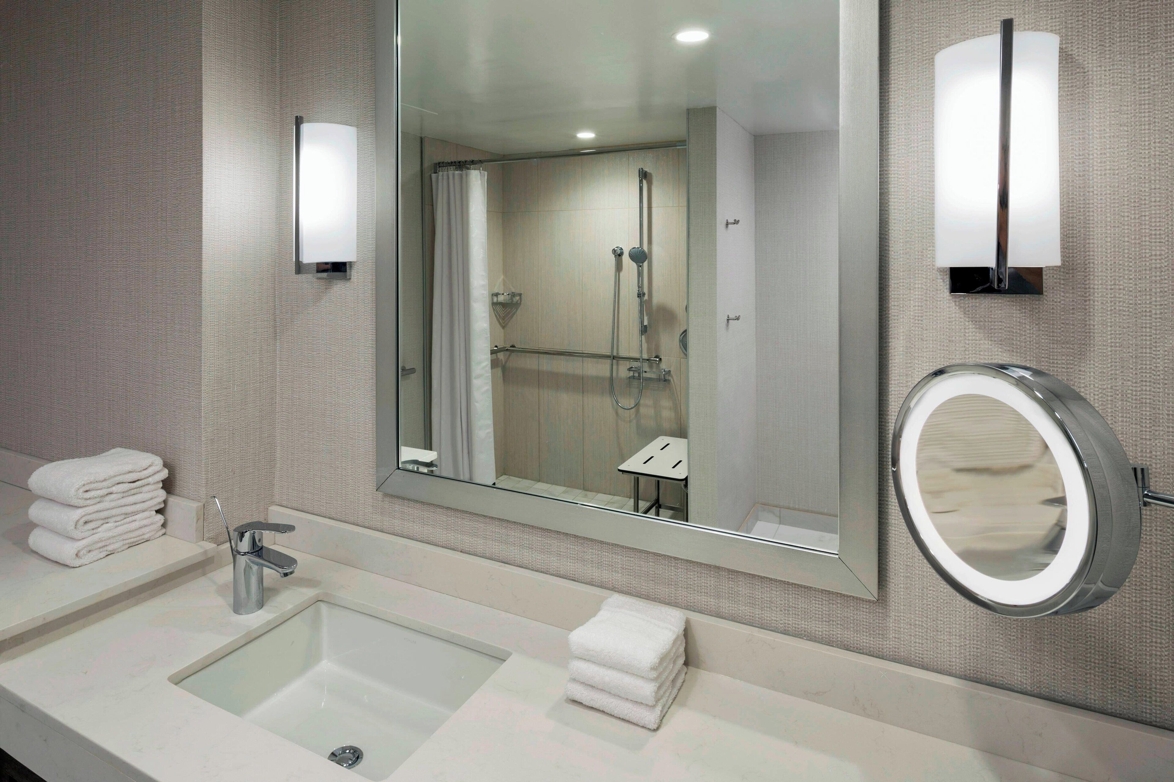 A modern bathroom with a large mirror, a sink, and a shower.