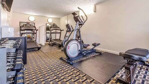 Un gimnasio con cintas de correr, elíptica, mancuernas y un banco.
