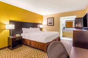 A hotel room with a bed, nightstand, lamp, and a television. - Ramada by Wyndham Santee I-95 (Santee)
