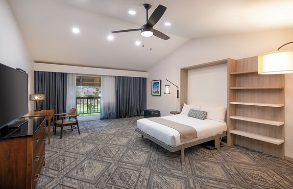 A modern hotel room with a bed, desk, chair, and a ceiling fan. - Half Moon Bay Lodge (Half Moon Bay)