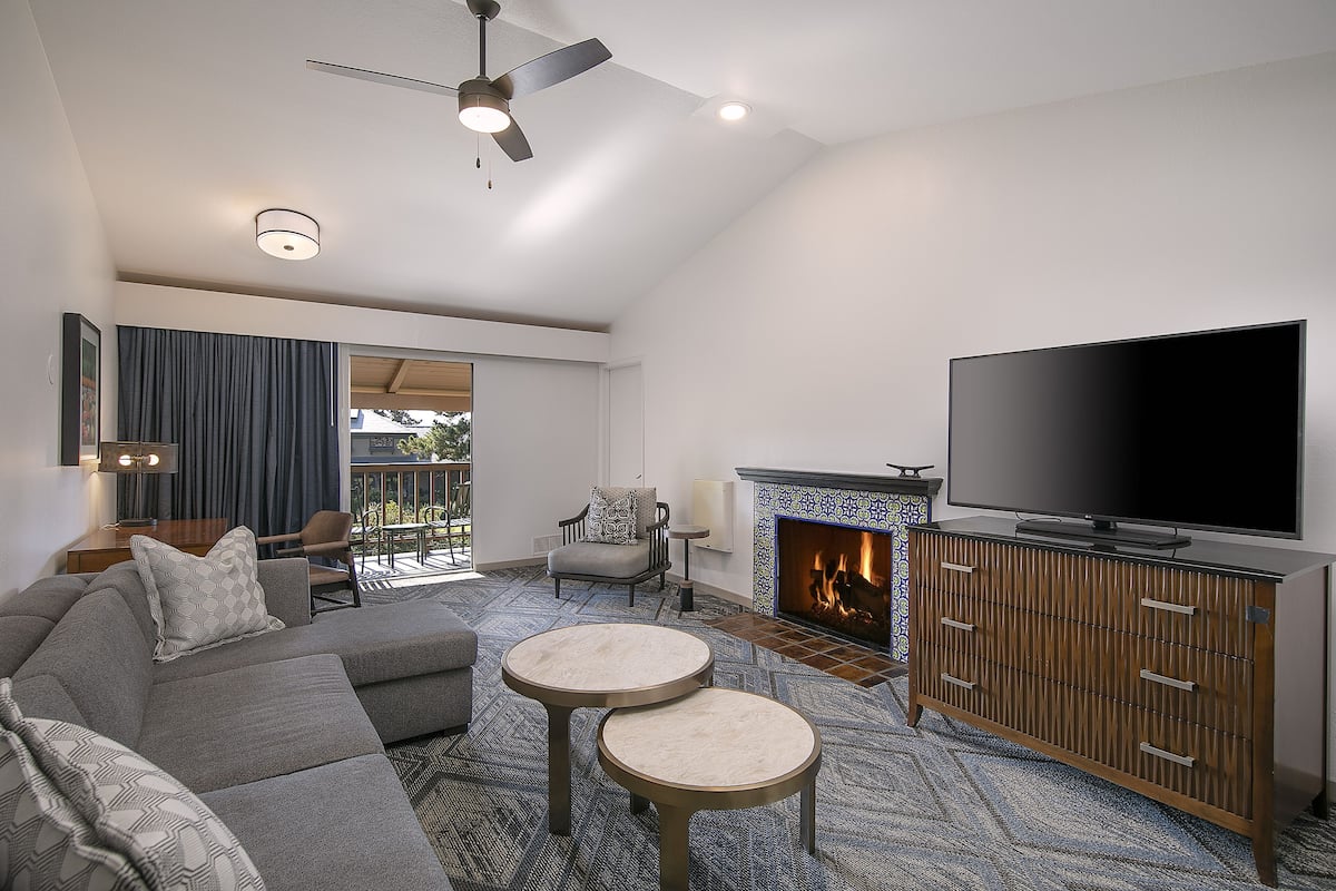 A modern living room with a sectional sofa, two round coffee tables, a flat-screen TV, and a fireplace.