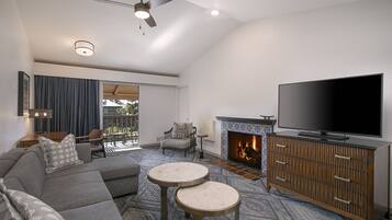 A modern living room with a sectional sofa, two round coffee tables, a flat-screen TV, and a fireplace.