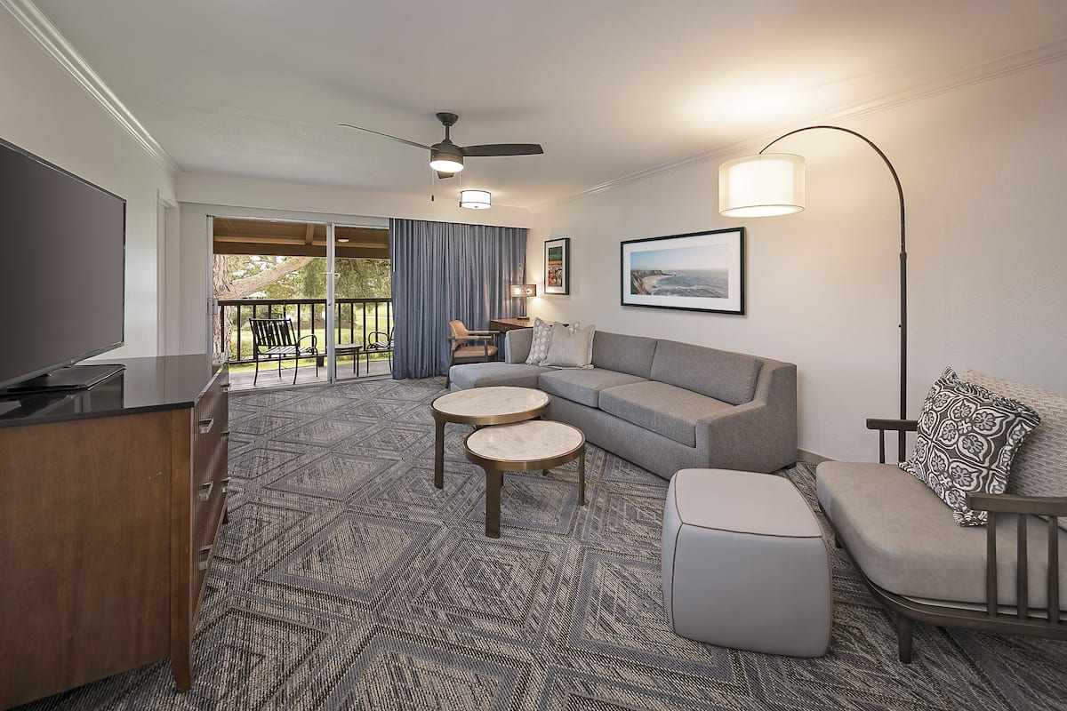 A modern living room with a grey sofa, two round coffee tables, a TV, and a ceiling fan.