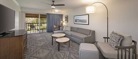 A modern living room with a grey sofa, two round coffee tables, a TV, and a ceiling fan.