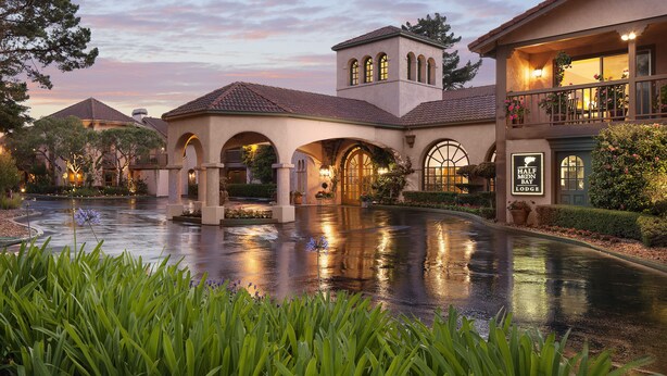 Un hotel con un patio, paseos con arcos y un letrero que dice "Half Moon Bay Lodge".