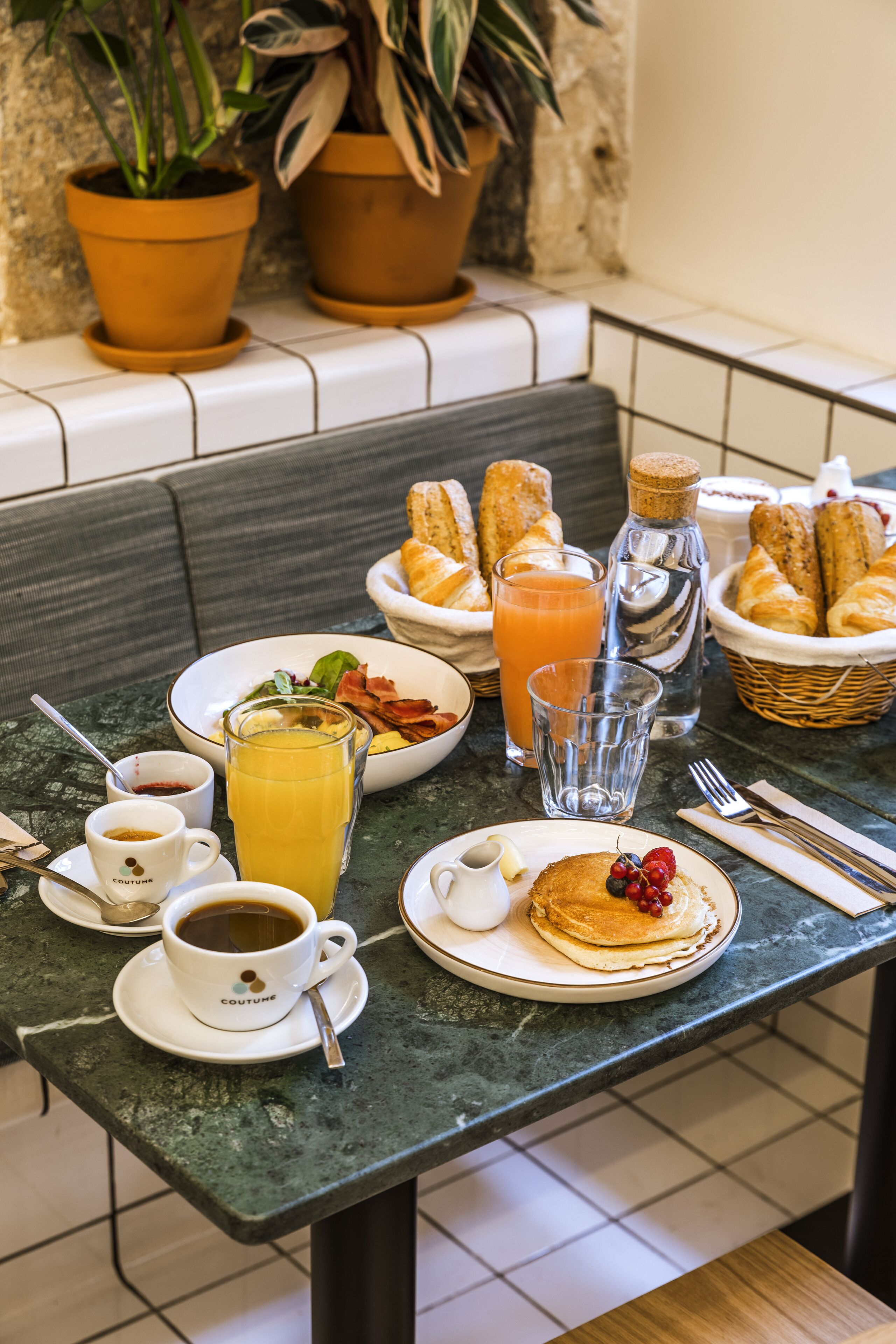 Een ontbijttafel met borden eten, een glas sinaasappelsap en een koffiekop.