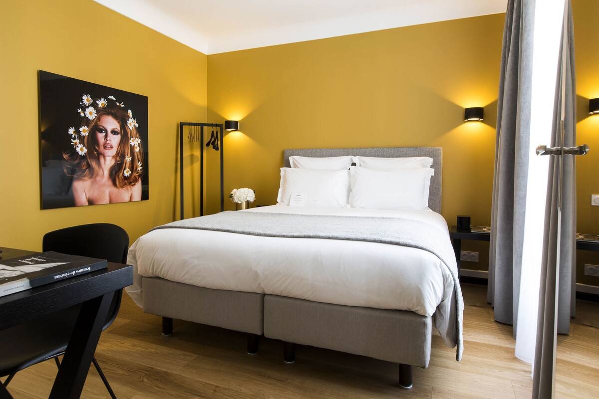 Habitación de hotel con una cama grande, un escritorio y una lámpara fijada a la pared.