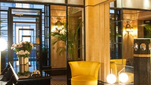 A lobby with a piano, a yellow armchair, and a black sofa. - Hôtel Mathis (Paris)