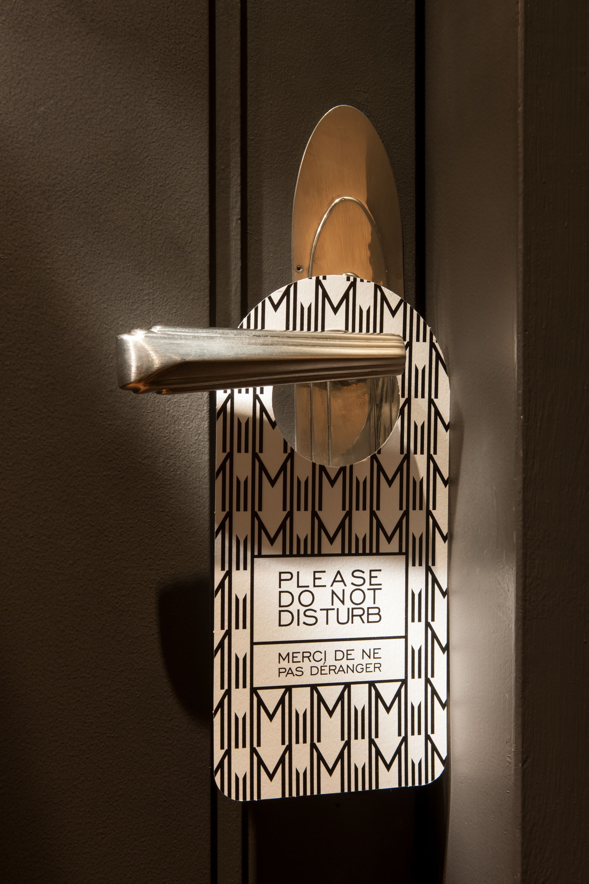 A door with a sign that reads "PLEASE DO NOT DISTURB" and "MERCI DE NE PAS DÉRANGER" in English and French.