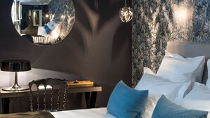 A bedroom with a bed, a round mirror, a desk, and a chair. - Hôtel Mathis (Paris)
