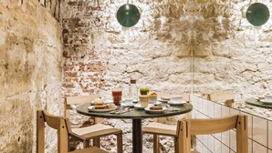 A rustic dining area with exposed brick walls, wooden chairs, and a round table with plates and cutlery. - Hôtel Mathis (Paris)