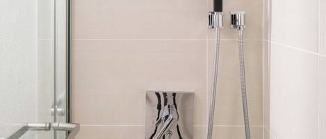 A modern shower with a handheld showerhead and a wall-mounted faucet.