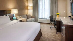 A hotel room with a large bed, a desk with a computer, a chair, a lamp, and a window with curtains. - Best Western Plus Strongsville Cleveland (Strongsville)