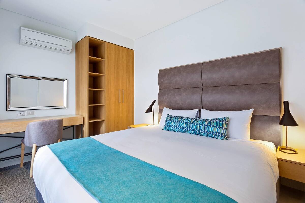Ein Hotelzimmer mit einem großen Bett, einem Schreibtisch, einem Sessel, einem Kleiderschrank und einem Fernseher.