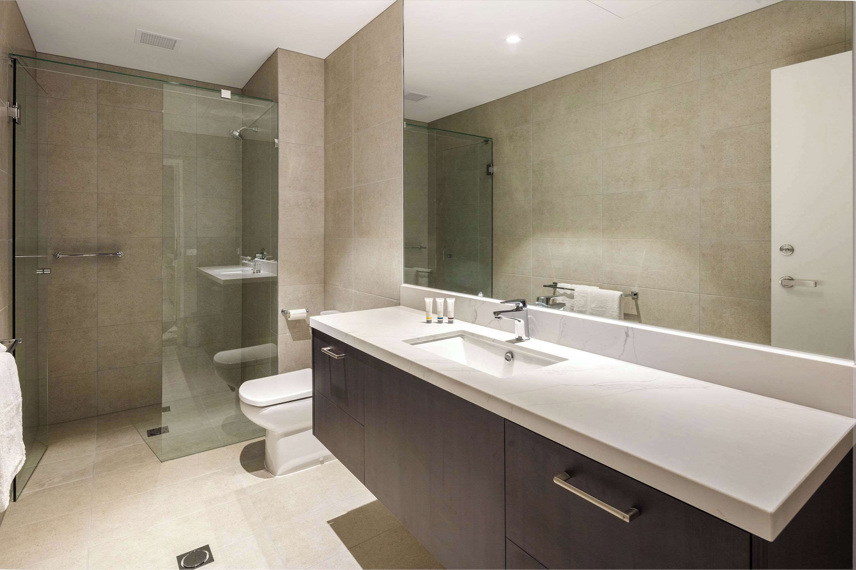 A modern bathroom with a glass-enclosed shower, a white sink, and dark cabinetry.