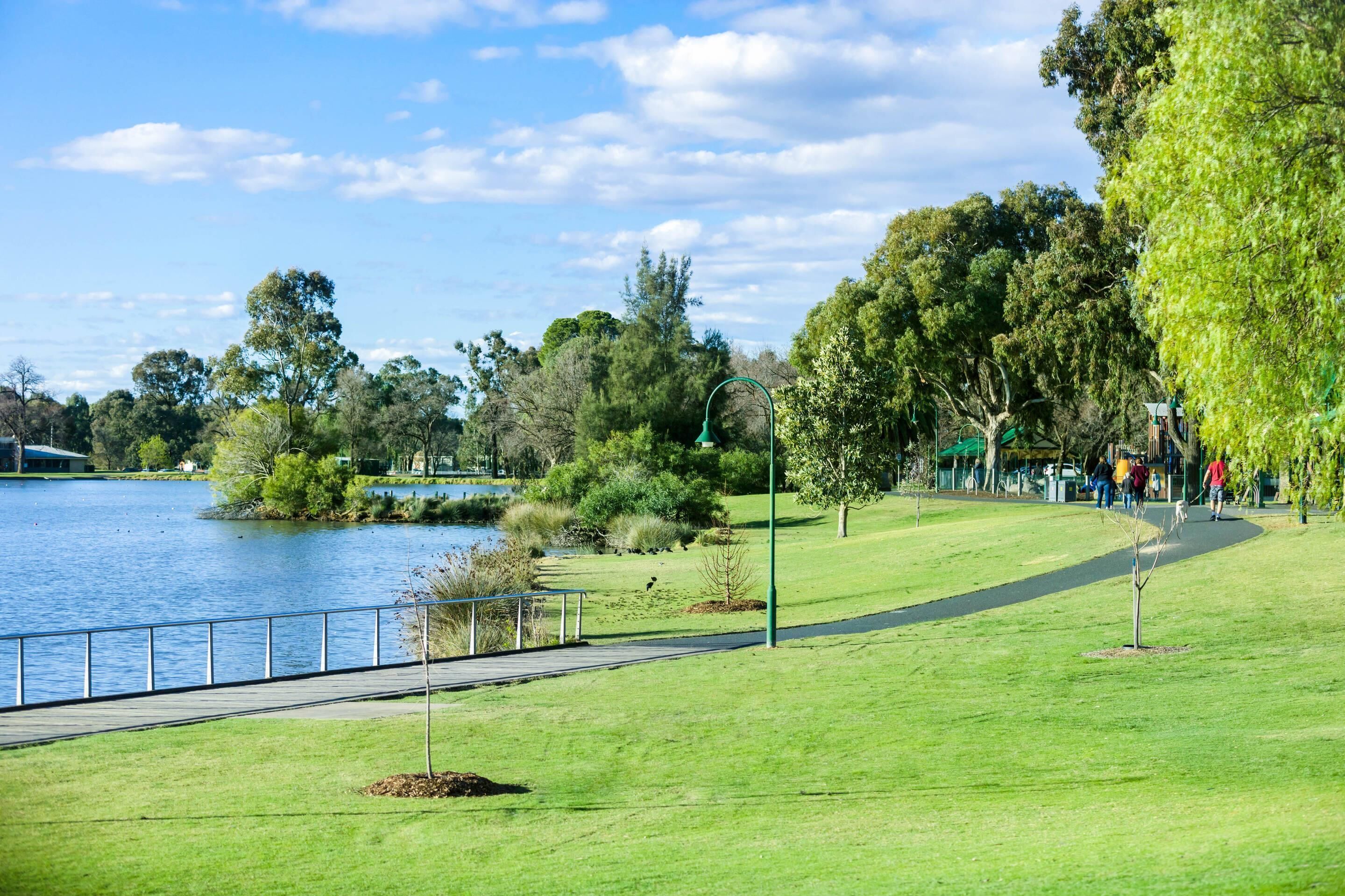 Un parque con un lago, senderos peatonales y árboles.