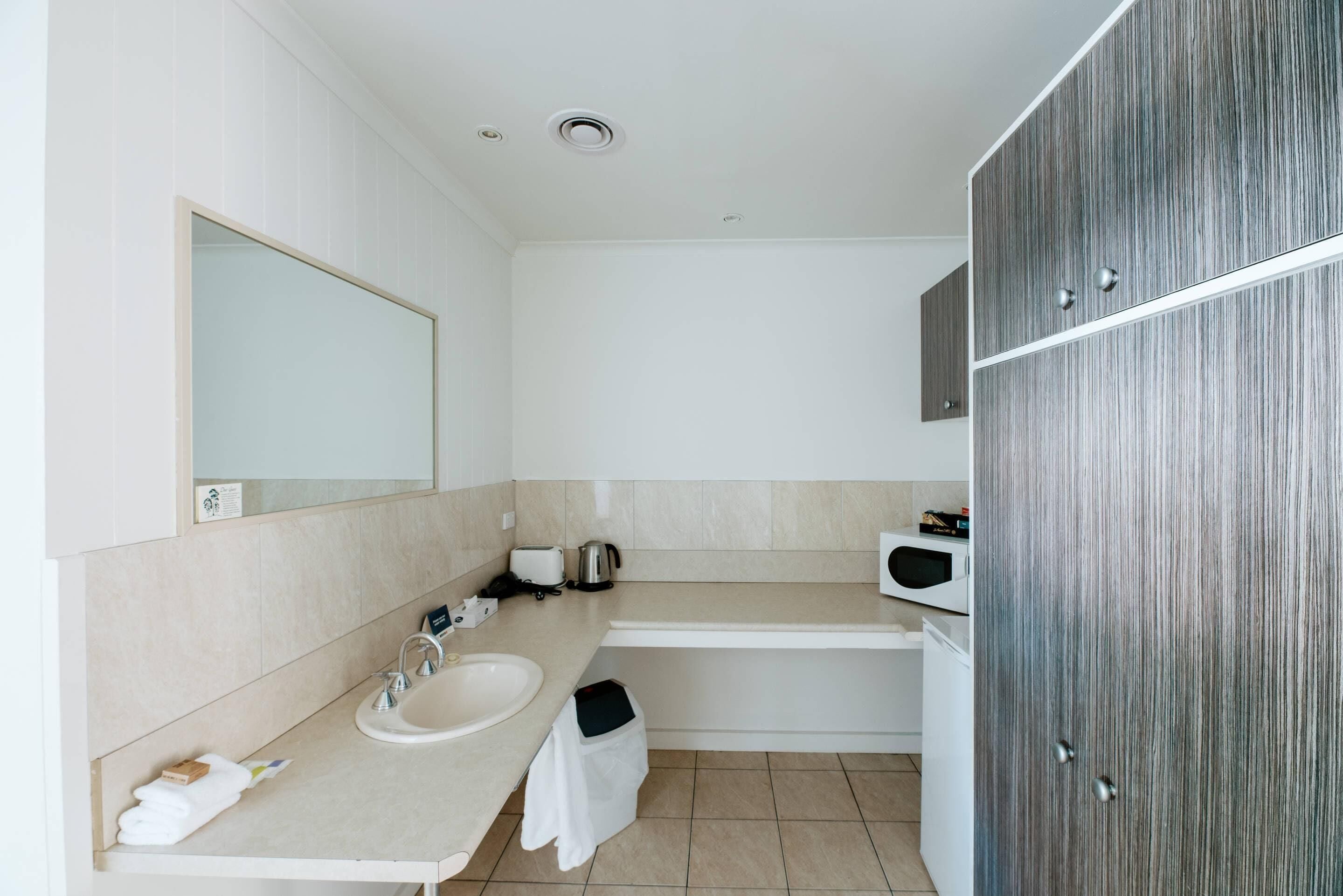 Un baño moderno con lavamanos, espejo y un mueble de madera.