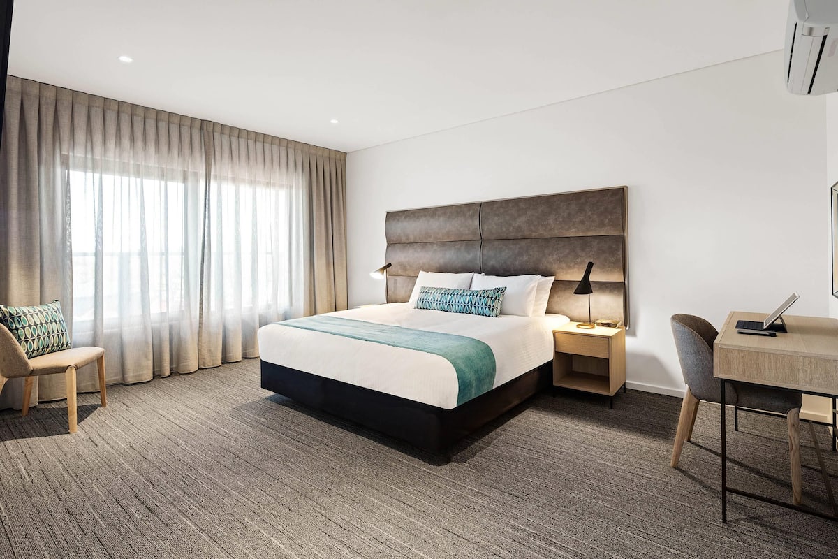 Ein modernes Hotelzimmer mit einem großen Bett, einem Schreibtisch und einem Sessel.