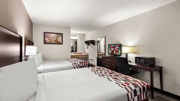 A hotel room with two beds, a desk with a television, a mirror, and a window.