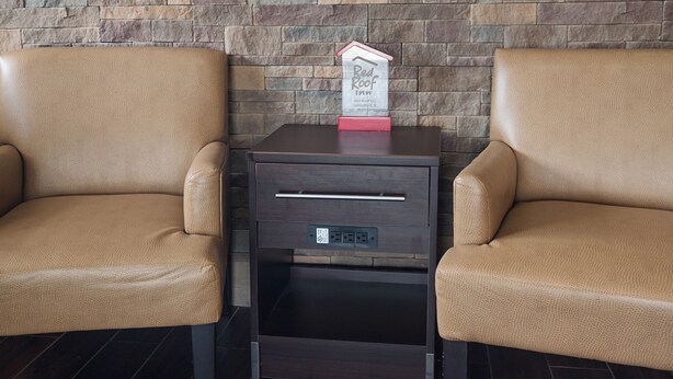 A hotel room with two leather armchairs, a small wooden nightstand with a Red Roof Inn sign, and a built-in drawer unit. - Red Roof Inn Springfield, IL (Springfield)