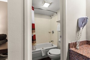 A bathroom with a bathtub, toilet, and a hairdryer mounted on the wall. - Red Roof Inn Springfield, IL (Springfield)