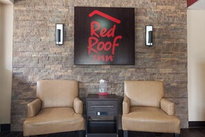 A wall with a sign reading 'Red Roof Inn' and two armchairs with a small table between them.