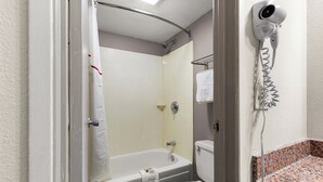 A bathroom with a bathtub, toilet, and a hairdryer on the wall. - Red Roof Inn Springfield, IL (Springfield)