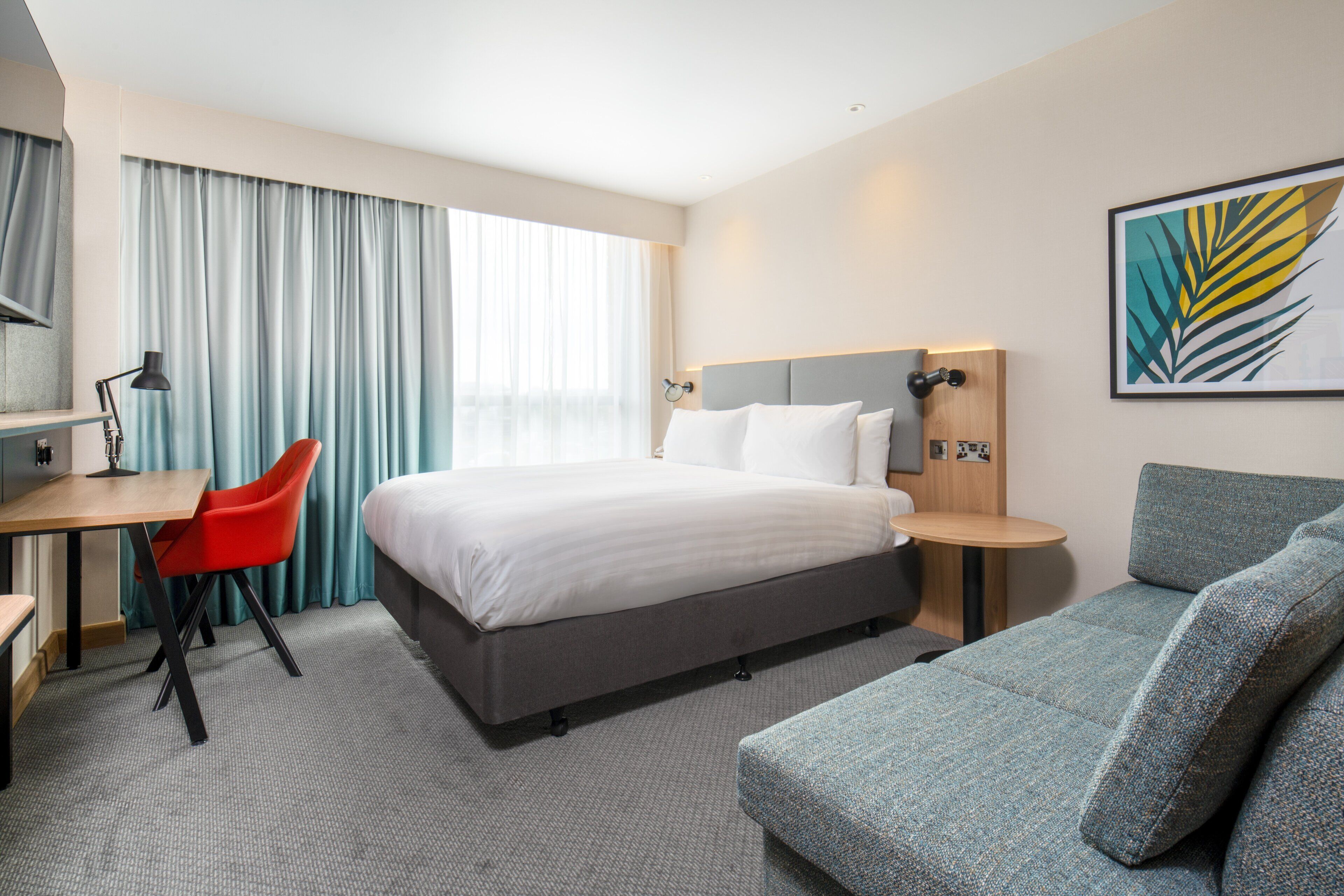 Ein Hotelzimmer mit Bett, Schreibtisch, Stuhl und einer Couch.