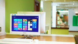 A Lenovo desktop computer on a desk with a keyboard and mouse, a green wall in the background, and a wooden counter. - Holiday Inn London - Heathrow M4,jct.4 by IHG (West Drayton)