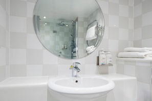 A bathroom with a round mirror, a sink, and a shower. - Holiday Inn London - Heathrow M4,jct.4 by IHG (West Drayton)
