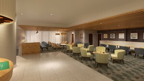 Un hall d’hôtel comprenant un comptoir d’accueil, un espace salon avec des fauteuils et des tables, et un tapis à motifs.