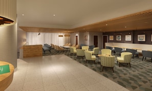 Un hall d’hôtel comprenant un comptoir d’accueil, un espace salon avec des fauteuils et des tables, et un tapis à motifs.