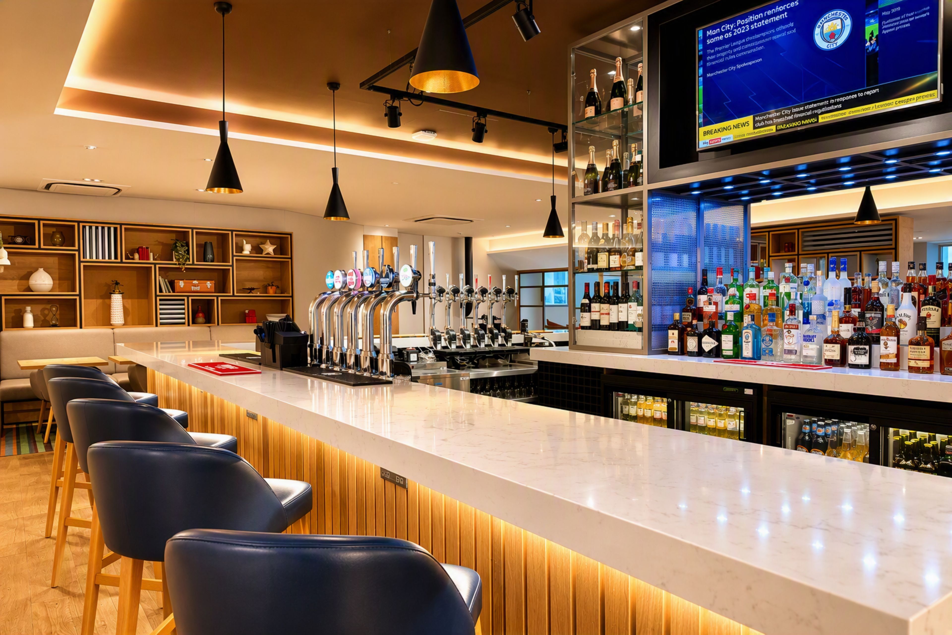 Área de bar com balcão extenso, várias torneiras e uma televisão exibindo notícias.