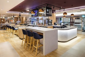 Un espace bar moderne comprenant un comptoir, des tabourets et une variété de bouteilles et de verres.