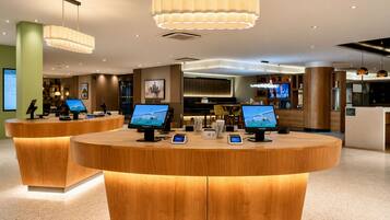 A modern reception area with wooden reception desks, multiple monitors, and pendant lighting.