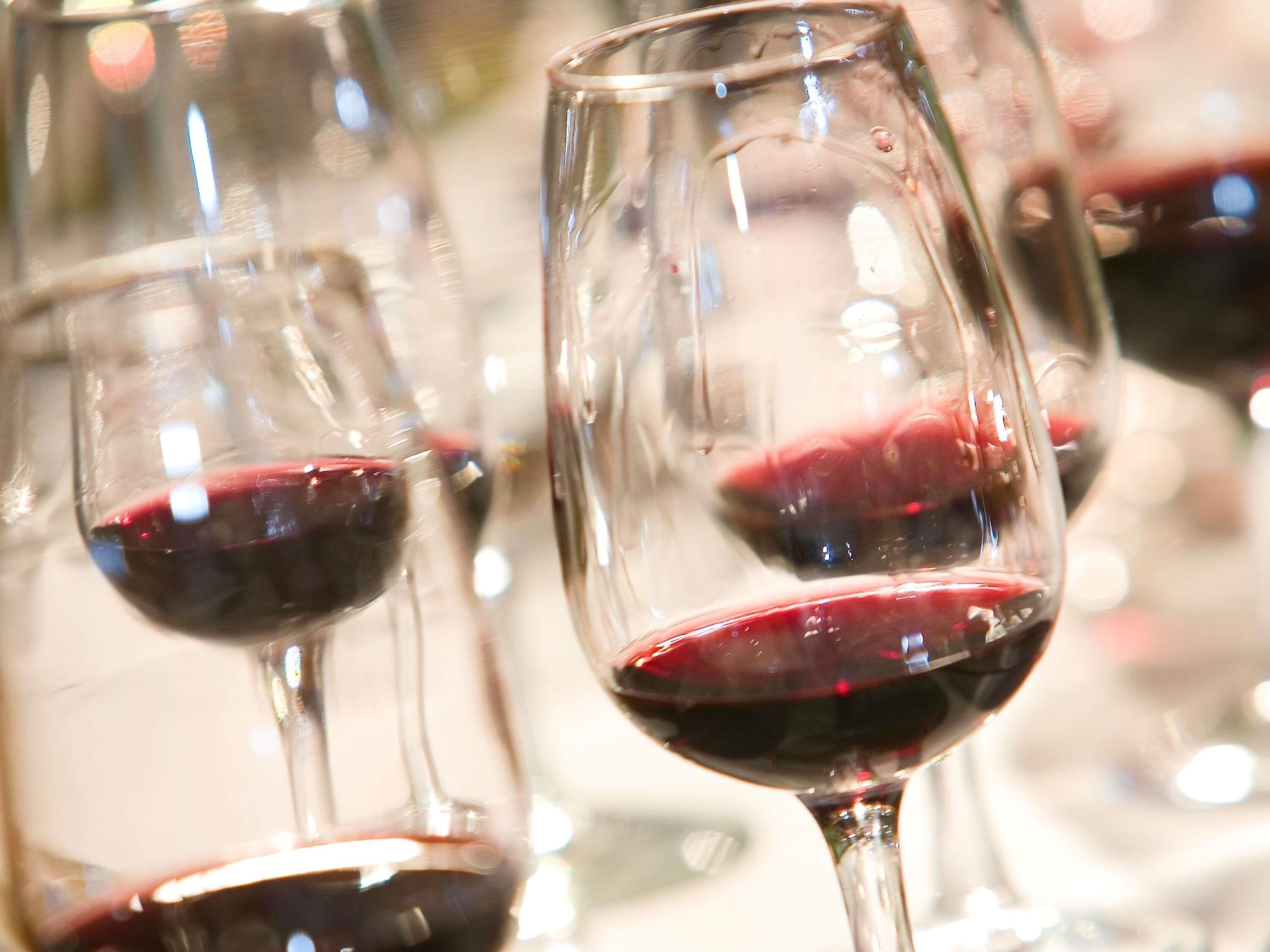 Multiple wine glasses filled with red wine, likely in a dining setting.