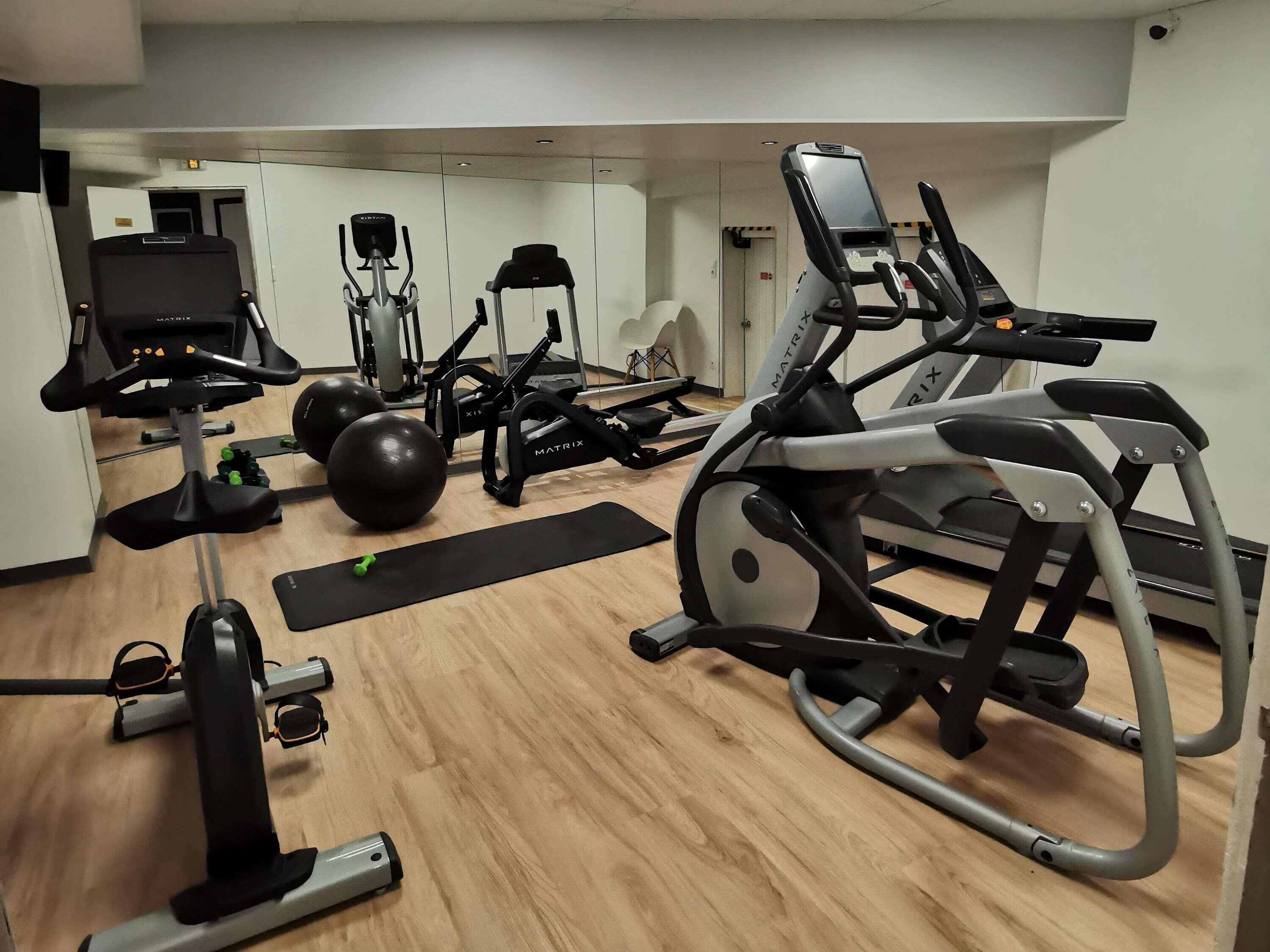 A gym with cardio machines, weight balls, and a treadmill.