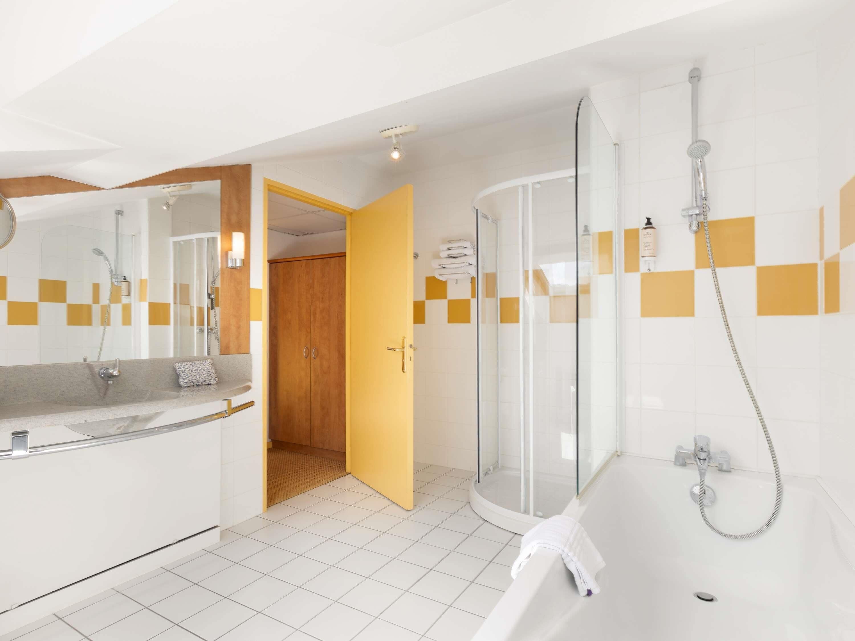 A modern bathroom with a shower, a bathtub, and a vanity with a mirror.