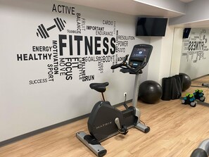 A gym with an exercise bike, a stationary bike, and various fitness equipment.
