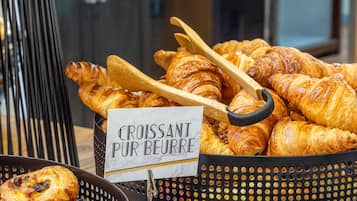 A display of croissants and pastries in a basket with a sign reading "Croissant Pur Beurre".