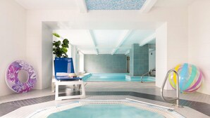 Et poolområde med jacuzzi, liggestole og en solstol ved poolen.