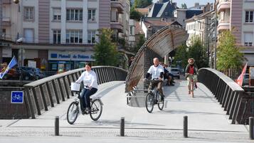 A pedestrian bridge with a curved metal railing, surrounded by buildings with balconies and storefronts.