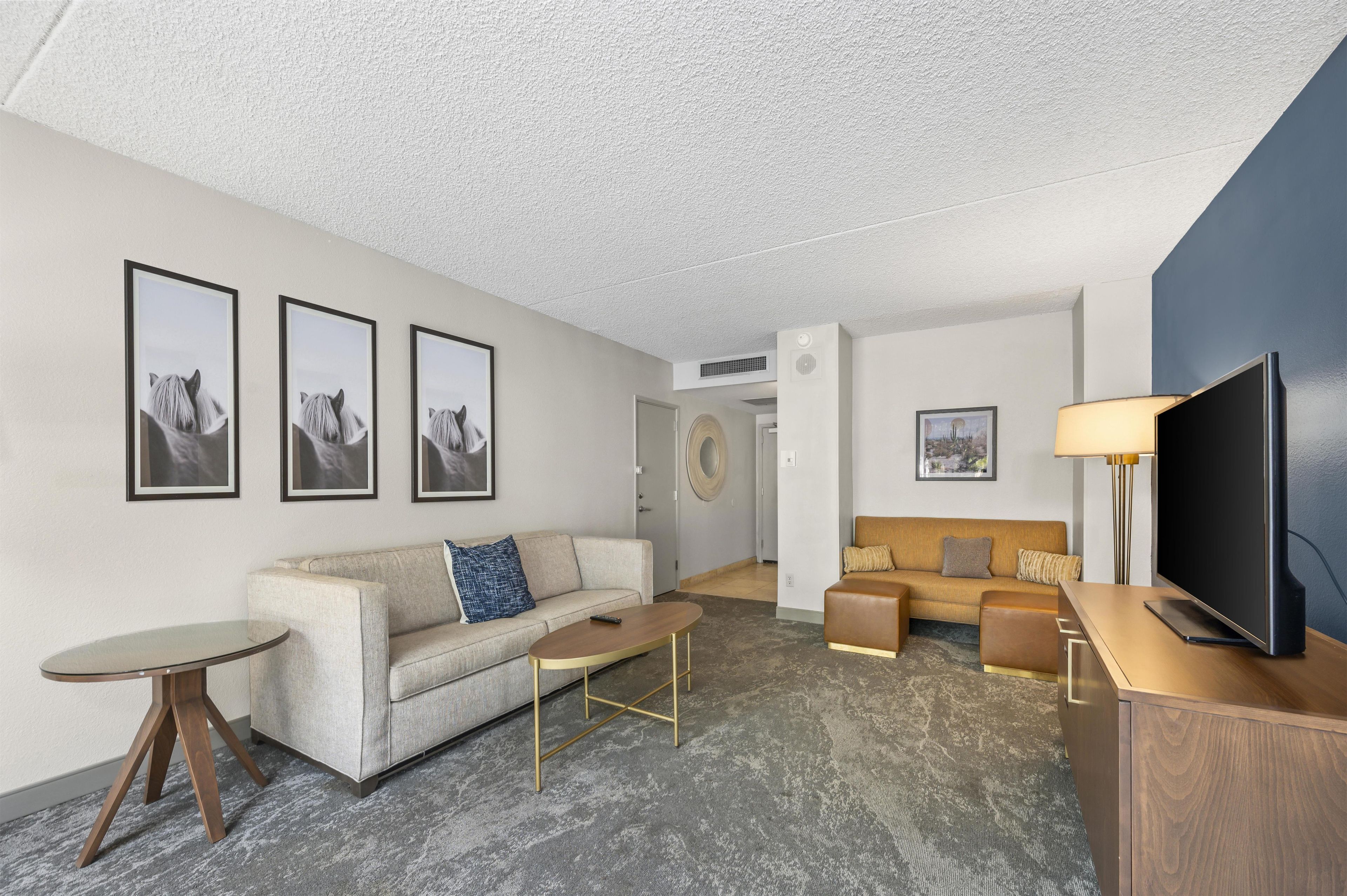 A modern living room with a sofa, a coffee table, a TV, and framed pictures on the wall.