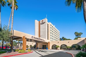 A DoubleTree hotel with a modern facade, large arched entrance, and palm trees in the foreground.
