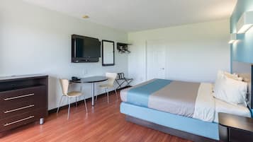 A hotel room with a bed, a desk, a chair, a television, and a wardrobe.