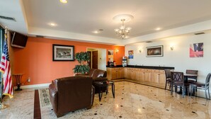 A spacious living area with a large brown leather sofa, a dining table with chairs, a kitchen area with wooden cabinets, and a chandelier. - Motel 6 Lexington, VA (Lexington)