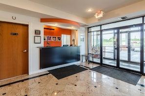 A reception area with a wooden door, a black reception desk, and a glass door leading outside.